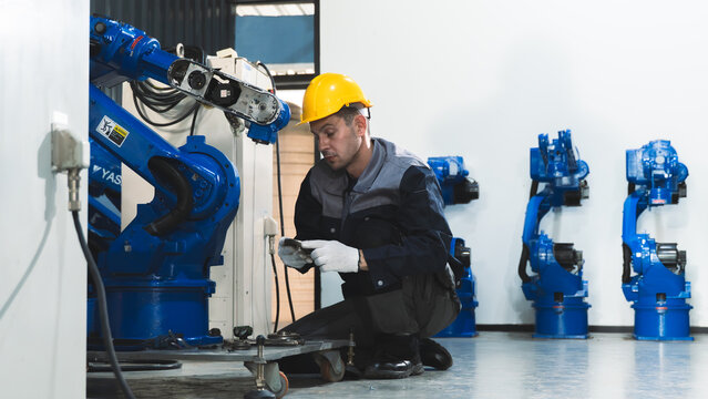 Industrial engineer troubleshooting machine performance Beside a Robotic Arm in a Modern Automated Manufacturing Facility