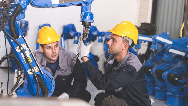 Factory Engineering Team assessing industrial machinery Next to an Automated Robotic Arm in an Industrial Workshop Scene 253