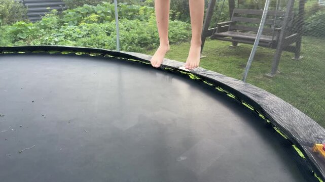 Child girl jumping on trampoline in backyard, active outdoor play scene