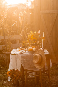 Cozy autumn table decoration for a thanksgiving party outdoors. Centrepiece with sunflowers, candles, pumpkins as decor. Elegant wedding fall arrangement, beautiful setting for a romantic lunch.