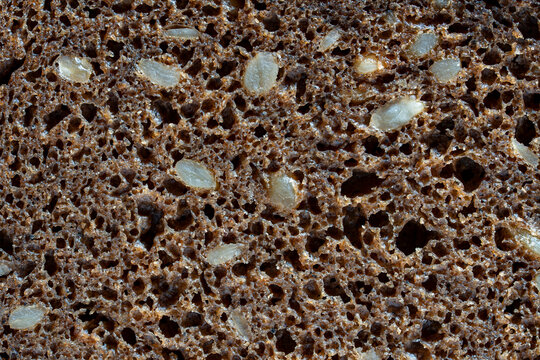 Macro texture of rye brown bread with seeds. Closeup full frame background of porous dark rye bread texture filled with whole grain seeds healthy organic food concept