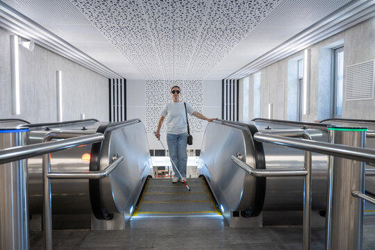 A blind woman rides an escalator in the subway.