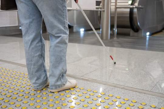 A blind woman in the metro near an escalator follows tactile navigation tiles.