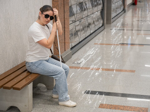 A blind woman waits for a train on the subway.