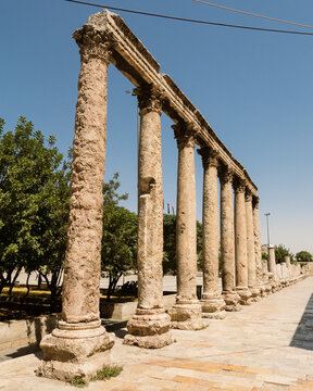 View of the ancient Roman Theater colonnade with weathered stone columns standing against a clear blue sky in Amman, Amman Governorate, Jordan.