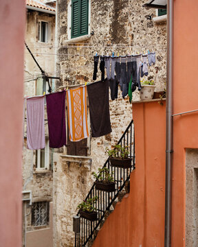 View of laundry hanging on a clothesline between historic stone buildings in an old town alley in Rovinj, Istria County, Croatia.