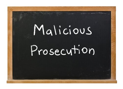 Malicious prosecution written in white chalk on a black chalkboard isolated in a wooden frame on white