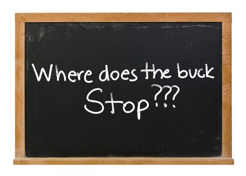 Where does the buck stop written in white chalk on a black chalkboard isolated in a wooden frame on white