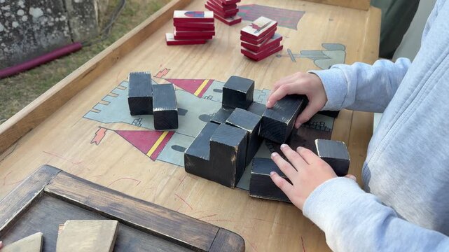 Children stacking wooden blocks in tabletop game, hands close up