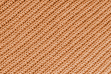 Close up, macro of orange knitted fabric texture with visible diagonal yarn stitches and soft wool pattern. Cozy textile backdrop, cloth background, fashion wallpaper, winter clothing concepts © katyamaximenko