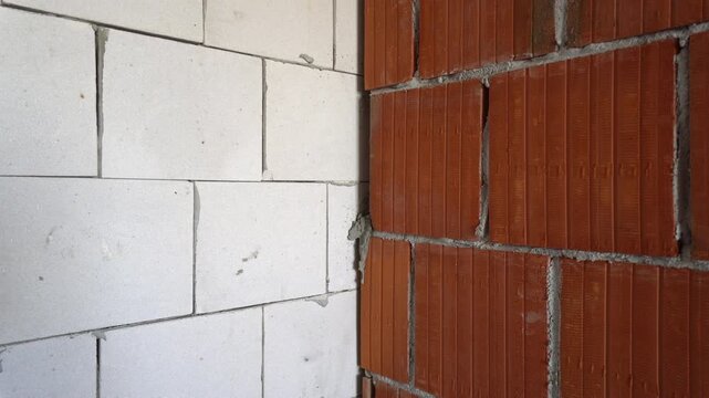 Construction site detail showing junction of white thermal block wall and red hollow clay block wall.