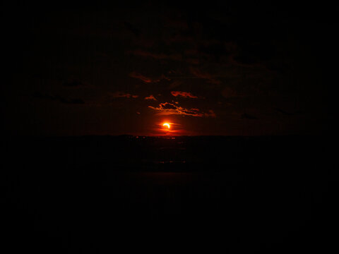 View of a partial solar eclipse over the dark waters of the Baltic Sea at Vakarbulli Beach in Riga, Latvia.