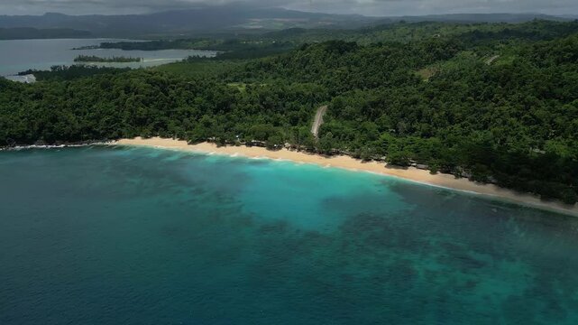 Aerial view of Paal Beach with turquoise waters, sandy shoreline, and lush tropical forest in Likupang Timur, North Sulawesi, Indonesia.