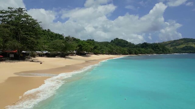Aerial view of Paal Beach with turquoise waters, sandy shore, and lush green trees in Likupang Timur, North Sulawesi, Indonesia.