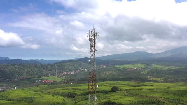 Aerial view of a telecommunications tower standing amidst the lush green tea plantations of Kayu Aro, Kab. Kerinci, Jambi, Indonesia.