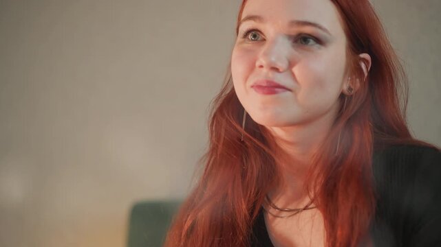 Intimate caucasian tarot reader looking down, redhaired woman in candlelit room with contemplative expression, soft lighting, subtle smile, beginning of card reading in cozy bohemian setting