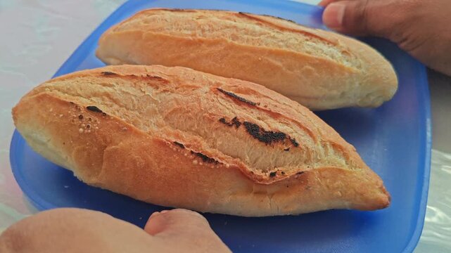 Hands Arranging Slices of Toasted Crusty Bread Rolls on Plate