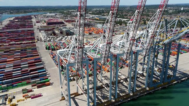 Southampton, United Kingdom - 15 August 2026: Aerial view of the Port of Southampton with rows of colorful shipping containers and large gantry cranes under a clear blue sky.