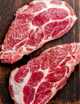 Raw pork cutlet chop for fry on pan with herbs, garlic on wooden boards, slate gray background