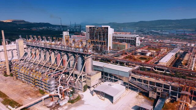 Footage over heavy industry processing machinery. Complex panorama of intricate network grids of vertical chemical reactors and metal pipe systems.