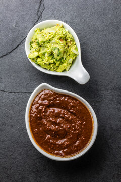 Traditional famous mexican sauces chocolate chili mole poblano, and avocado guacamole on slate gray background