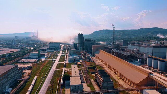 Vast factory landscape with steaming vents. Sprawling manufacturing complex nestled against rolling green hills.