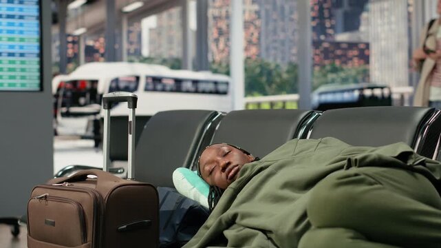 Tired woman rests on bus terminal seats during a long wait for a cancelled departure to resume, sleeping on baggage during the delayed coach journey.