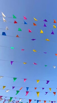 Multicolored triangular small flags to celebration party against blue sky. Street holiday concept,4K.	