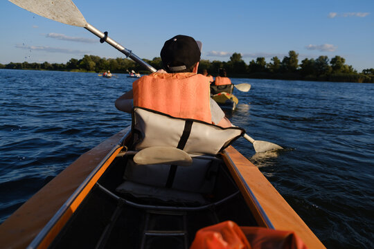 Boy in life jacket kayaking on calm river water during sunny summer day, outdoor active lifestyle and water sport concept