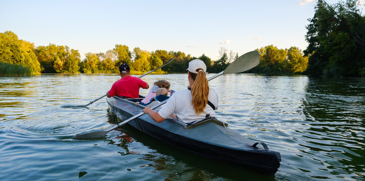 Active family with children kayaking on scenic calm river, outdoor summer adventure, water sport leisure and travel concept