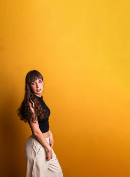 Young woman with bangs posing against yellow background