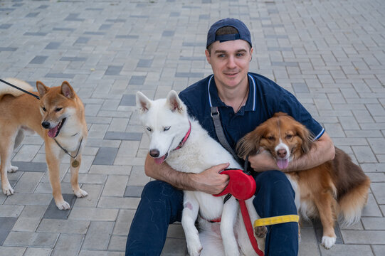 A man hugs his two dogs while on a walk. 