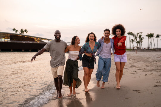 A diverse group of multicultural friends enjoying summer moments on the beach, dancing, laughing