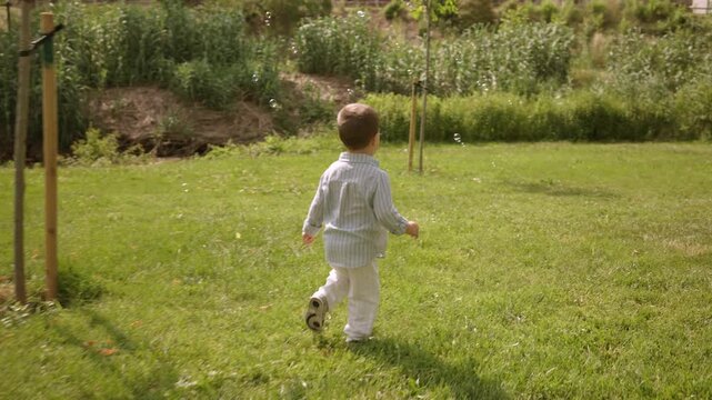 Happy toddler boy running in green park on a sunny day
