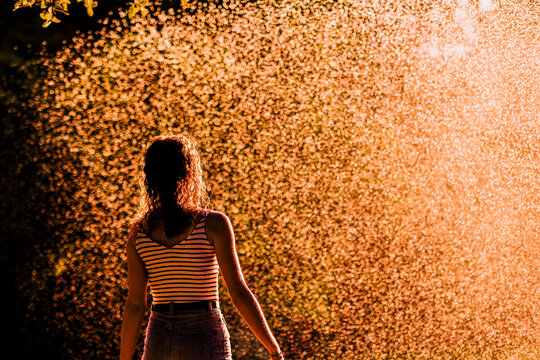 Young woman enjoying summer rain or sprinkler