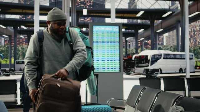 Tired passenger struggles with heavy baggage in a bus terminal before an intercity route, moving bulky luggage toward a bench in the shuttle station.