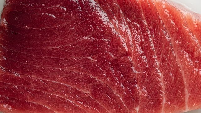 Close-up texture of a fresh raw tuna steak with vibrant red flesh and visible muscle fibers