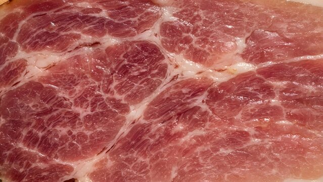 Close-up texture of raw pork meat with visible marbling of fat and muscle fibers.