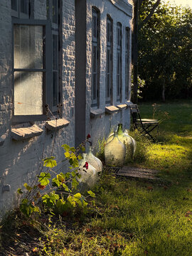 Glass demijohns standing by cottage wall in rural Germany