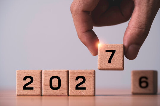 Hand changing wooden number blocks from 2026 to 2027 symbolizes New Year transition, future business planning , fresh start goals, calendar change, strategy and preparation for new opportunities.