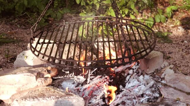 Glowing coals and burning wood in barbecue fire pit, barbecue camping concept, flames, BBQ fire pit grilling over open fire, outdoor feast, rustic adventure lifestyle, outdoor feast, nature experience
