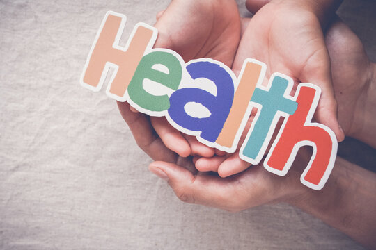 Health, Hands, Wellness, Support, Family, Care, Protection concept of healthcare and medical insurance with adult and child hands holding a colorful word sign for wellbeing.