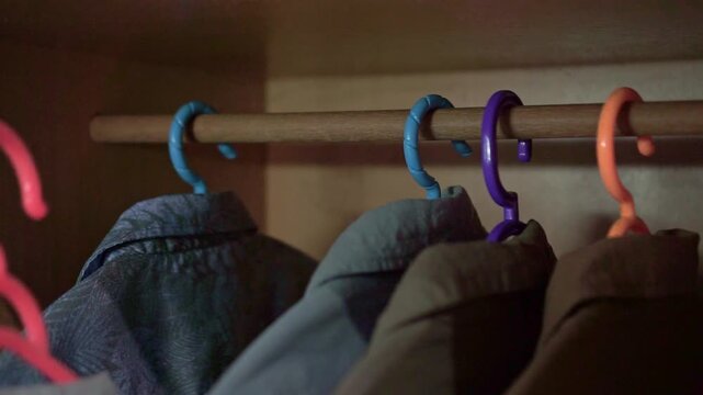 Hand returning a clothes hanger into a wardrobe. Perfect for home organization, clothing storage, closet management, and everyday household routine concepts.