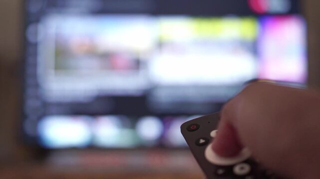 hand holding remote control, changing TV channel. Smart TV streaming concept, home entertainment, lifestyle stock footage.