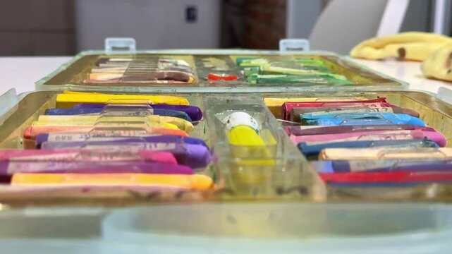 Kid hand selecting wax crayon from colorful collection, close up shot, art supplies and coloring materials concept.