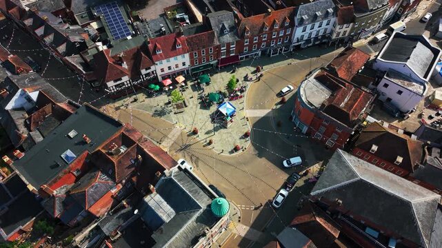 Top-down drone shot of Romsey's historic market square, with caf&eacute; tables, shops and street lights strung overhead.