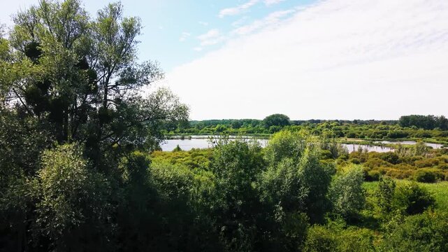 Drone shot over Fishlake Meadows' open lake and wetland scrub, surrounded by countryside near Romsey.