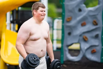 Workout begins on playground. Overweight workout shows effort. Outdoor workout with dumbbells. Workout supports healthy lifestyle. © Volodymyr