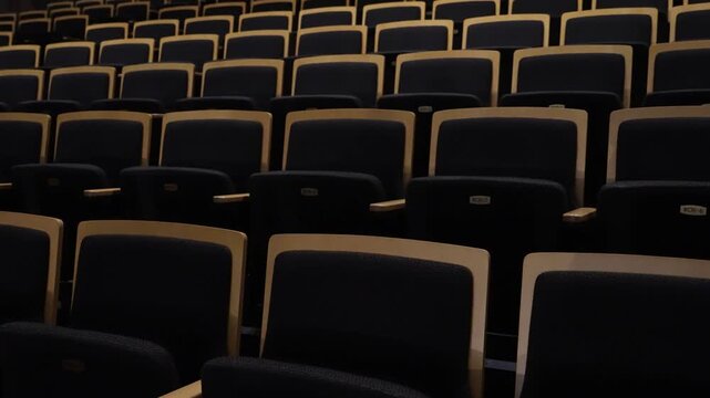 Horizontal shot of empty dark seats in a theater auditorium before a performance