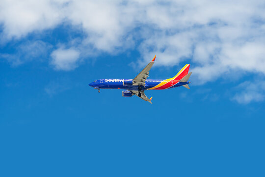 Tustin, CA, USA - August 7, 2026: A Southwest Airlines airplane in flight with landing gears out against a blue cloudy sky heading for a landing.